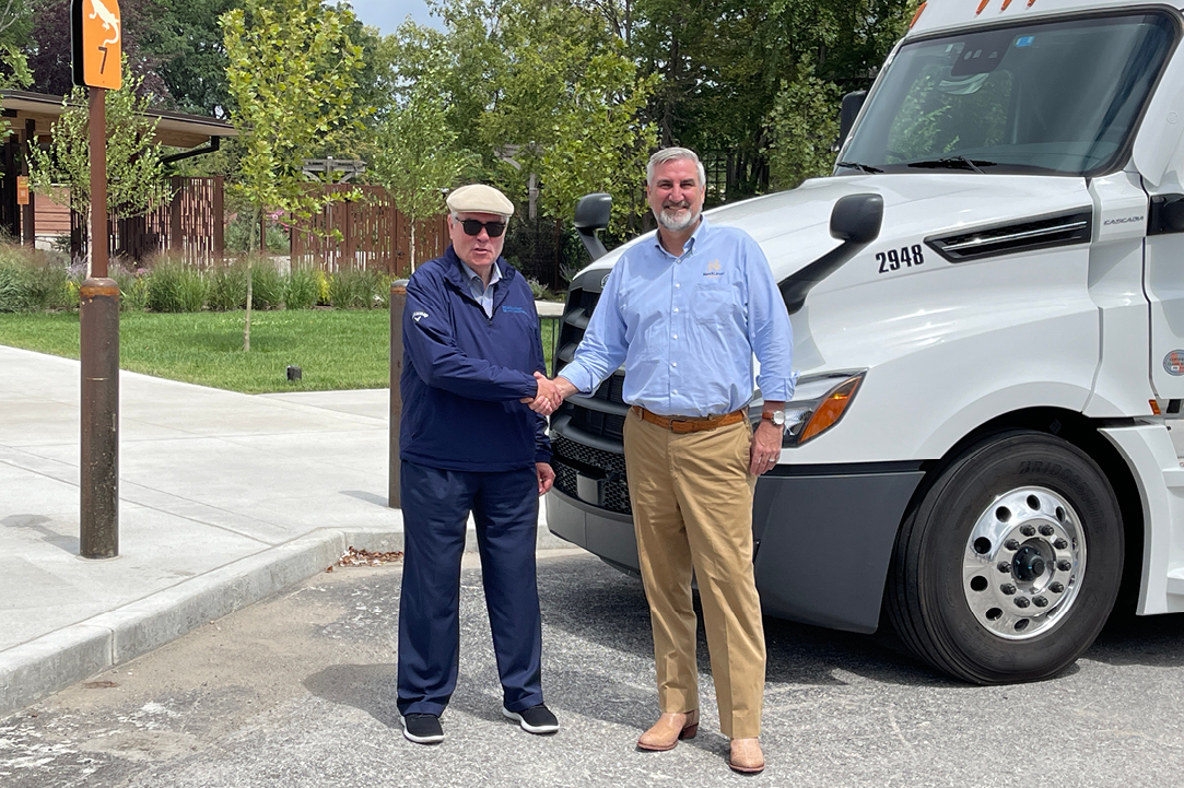 Geary Buchanan and Indiana Governor Eric Holcomb shaking hands in front of the Buchanan Hauling truck