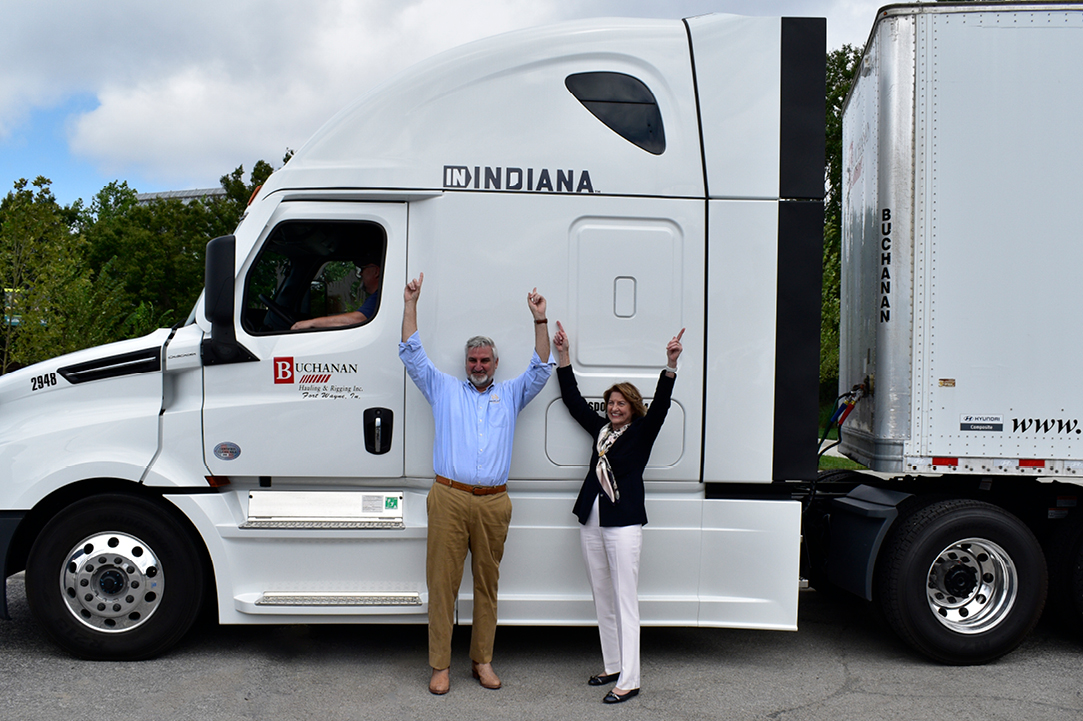 Indiana Governor Eric Holcomb points at the IN Indiana campaign logo on the side of the Buchanan Hauling and Rigging Truck