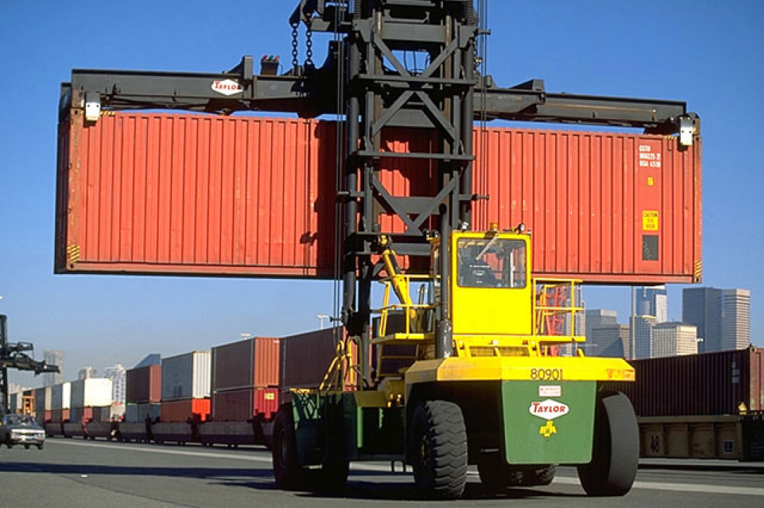Dock container loader prepares to set a drayage container for transport on a truck carrier.