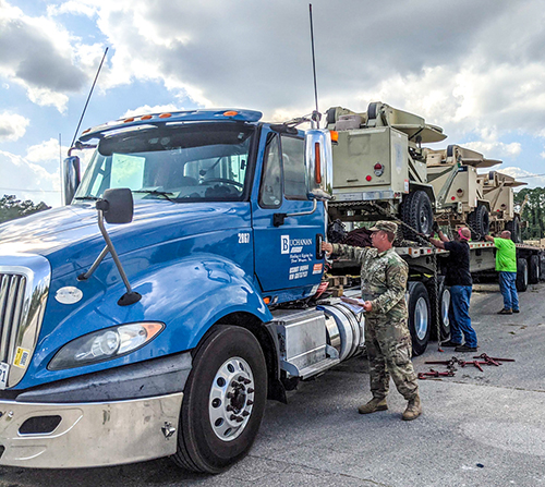 Military vehicles being loaded onto a Buchanan Hauling truck for transport.